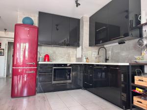 a kitchen with black cabinets and a red refrigerator at Petit Jardin de Paris in Gennevilliers