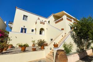 una grande casa bianca con piante in vaso di The Residence a Spetses