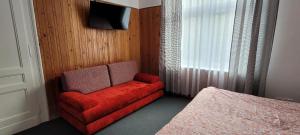 a red couch in a bedroom with a bed at Asnyk Prestige Apartments in Kraków