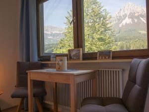 Cette chambre dispose d'une grande fenêtre, d'une table et de 2 chaises. dans l'établissement Apartment Studio Esche 2 by Interhome, à Ellmau