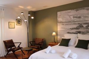 a bedroom with a bed with chairs and a painting at Chambres d'hôtes face à Bréhat, Maison des îles in Ploubazlanec +20 photos