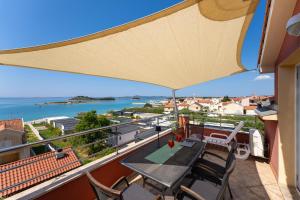 a balcony with a table and chairs and a view of the water at Apartments Villa SanMarino in Pakoštane