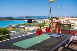 two wine glasses sitting on a table on a balcony at Apartments Villa SanMarino in Pakoštane