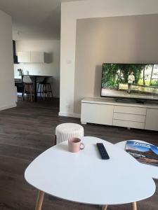 a living room with a white table and a tv at Maison de vacances entre forêt et plage in Saint-Jean-de-Monts