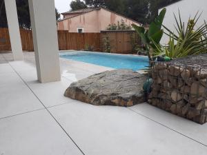 a swimming pool with a rock next to a yard at Pin D'Epice in Balaruc-les-Bains