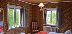 a bedroom with two windows and a bed and a chair at MUSES BNB Bed & Breakfast in Bergvik