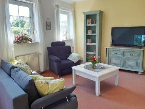 a living room with a couch and a table and a tv at Ferienwohnung am Heidesee in Faßberg