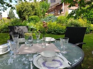 a glass table with a bowl and plates and glasses at Ferienwohnung am Heidesee in Faßberg