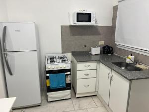 Una cocina con refrigerador, estufa y fregadero. en Depto Los Troncos, en Tandil