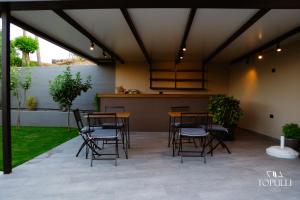 a patio with tables and chairs under a roof at Villa Topulli View in Gjirokastër