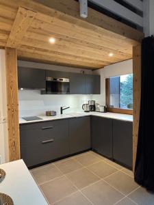 eine Küche mit grauen Schränken und einem großen Fenster in der Unterkunft Les Lucioles in Saint-Jean-de-Sixt