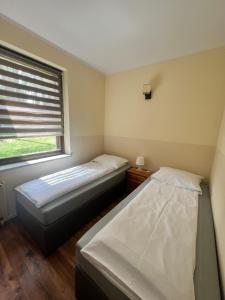 two beds in a small room with a window at Barnaba Domki in Pobierowo