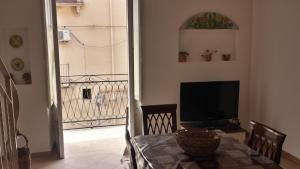 a dining room with a table with a television and a balcony at Garibaldi home Fabrizia in Castellammare del Golfo