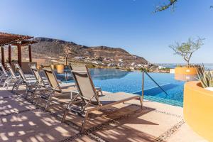 a row of chairs sitting next to a swimming pool at Luxurious Penthouse at Vistamar! Golf - Beachclub in La Paz