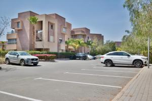 Un estacionamiento con autos estacionados frente a un edificio. en Jade Haven 2 Bed Apt golf view, en Marrakech
