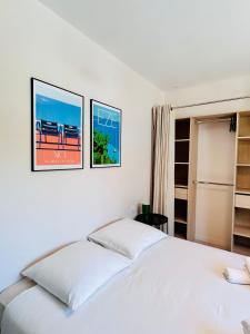 Coliving - Private Shower - Bfast & Terrace Dining في كاجنيس سور مير: غرفة نوم بسرير ابيض مع وجود صورتين على الحائط