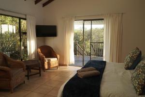 a bedroom with a bed and a tv and a balcony at Mazuri Bush Cottages in Hluhluwe