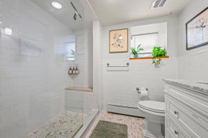 a white bathroom with a shower and a toilet at Jersey City Retreat w Private Backyard Bonfire Near NYC in Jersey City +16 photos