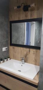 a bathroom with a white sink and a mirror at Nowoczesny apartament z dużym tarasem i widokiem na jezioro in Giżycko