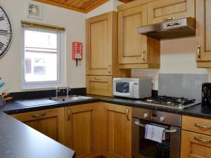 a kitchen with wooden cabinets and a sink and a microwave at Lodge G- Uk33093 in Dinnet