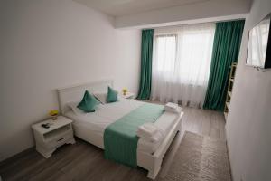a bedroom with a bed with green sheets and a window at Ana Derol in Năvodari