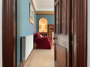 a hallway with a red chair in a room at Stanford House in Inverness