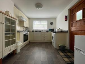 a kitchen with white cabinets and a washer and dryer at Stanford House in Inverness