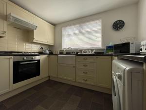 a kitchen with white cabinets and a clock on the wall at Stanford House in Inverness +15 photos
