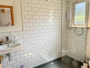 Baño de azulejos blancos con lavabo y espejo en Cluny, en Aberfeldy