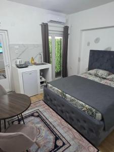 a bedroom with a bed and a table and a kitchen at AK mini studio u centru in Tivat