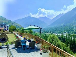 a balcony with tables and chairs and a view of mountains at ROYALE PEAKS villa sonamarg Rd  +4 photos