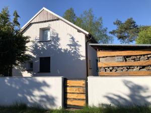 a white house with a wooden fence next to it at Domek Spokojna Przystań in Przybrodzin