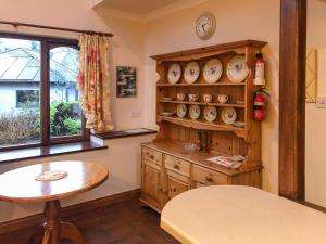 Una habitación con una mesa y un estante con relojes. en Forge Mill Cottage, en Dalbeattie