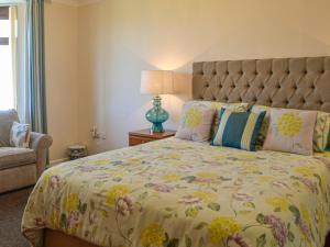 a bedroom with a large bed with a floral bedspread at Kinvara in Stranraer +12 photos