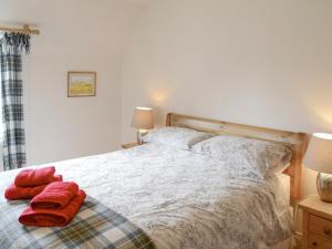 a bedroom with a bed with two red towels on it at Keeper's House in Glenrossal