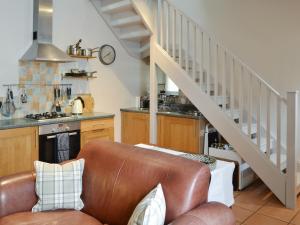 sala de estar con sofá de cuero y escalera en Youngers Cottage, en Warkworth
