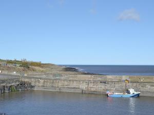 un pequeño barco en el agua junto a un muelle en Youngers Cottage, en Warkworth 2 fotos más