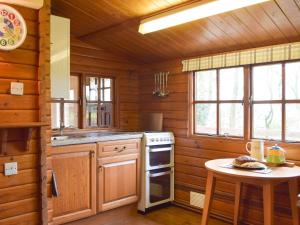 a kitchen in a log cabin with a table at The Orchard - Uk13182 in Cwm-Morgan