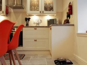 a small kitchen with white cabinets and red chairs at Rhunahaorine Cottage in Gortinanane