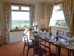 a dining room with a table and two windows at Bel-Mar in Whithorn