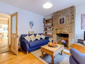 a living room with a blue couch and a brick fireplace at Anchor Cottage in Whitstable