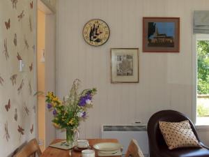 a dining room with a table and a clock on the wall at The Garden House - Uk10987 in Llandogo