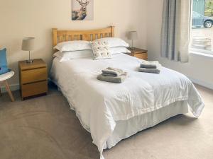Un dormitorio con una cama blanca con toallas. en Dalnafeidh Beag - Cottage, en Portnacroish