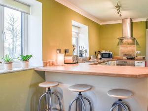eine Küche mit zwei Barhockern an der Theke in der Unterkunft Meadow Cottage in Gowerton