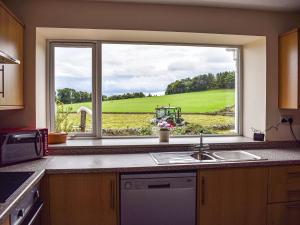 une fenêtre de cuisine avec vue sur un terrain de golf dans l'établissement Southview Cottage, à Cupar 19 autres photos