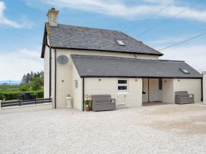 a white building with two chairs in front of it at Cuillin View Apartment - Uk12529 in Arisaig