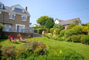 a house with two red chairs in the yard at Seascape in New Quay