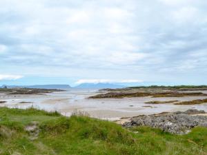 a beach with people walking on the sand at Cuillin View Apartment - Uk12529 in Arisaig