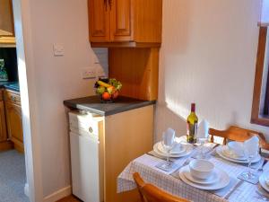 una cucina con tavolo, piatti e una bottiglia di vino di Butterhole Cottage a Kelton