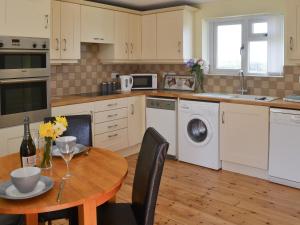 a kitchen with a wooden table and a dining room at The Cockles in Ulgham